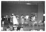 Students in various costumes perform on stage