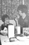 Two women sip coffee at table together by George Fox University Archives
