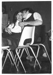 Male and female sit with feet up on chairs; male leans to talk to female by George Fox University Archives