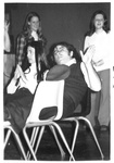Male and female sit with feet up on chairs; male waves to camera by George Fox University Archives
