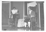 Male actor sits in chair while dusts behind another chair by George Fox University Archives