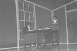 Actor sits at desk as another male actor stands at desk by George Fox University Archives