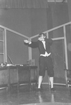 Actor stands at desk and pretends to shoot rifle by George Fox University Archives