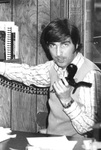 Barry Hubbell holds phone at desk by George Fox University Archives