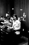 Staff member works at desk in office by George Fox University Archives