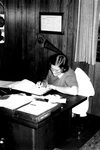 Staff member works at desk in office by George Fox University Archives