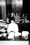 Two staff members work at office desks by George Fox University Archives