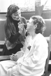 Female with face paint applies makeup on another students' face by George Fox University Archives