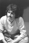 Male actor with dark hair sits on stage by George Fox University Archives
