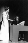Woman puts hand on man's shoulder, who is sitting at a desk by George Fox University Archives