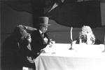 Alice sits at table with March Hare, Dormouse, and Mad Hatter