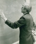 Don Millage writes numbers on a chalkboard by George Fox University Archives