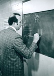 Sam Willard writes on chalkboard by George Fox University Archives