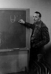 Sam Willard writes on chalkboard by George Fox University Archives