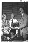 People Standing and Smiling Holding a Plaque at an Alumni Reception by George Fox University Archives